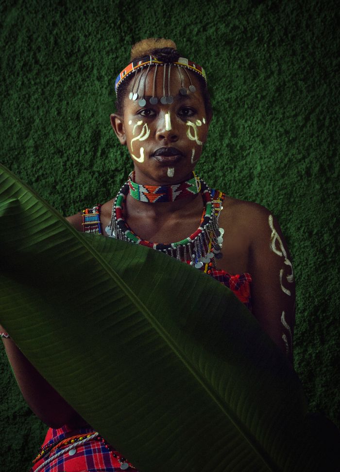 Striking portrait of a woman in traditional Kenyan attire with vibrant face paint and tribal accessories.